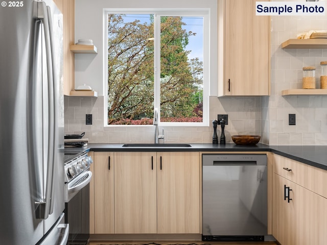 kitchen featuring open shelves, appliances with stainless steel finishes, dark countertops, a sink, and light brown cabinets