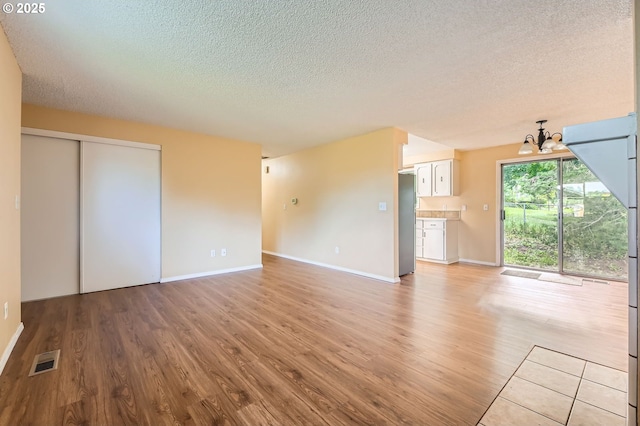 12172 SE Beckman Ave, Milwaukie, OR 97222 - unfurnished living room with a textured ceiling, light wood finished floors, and a chandelier