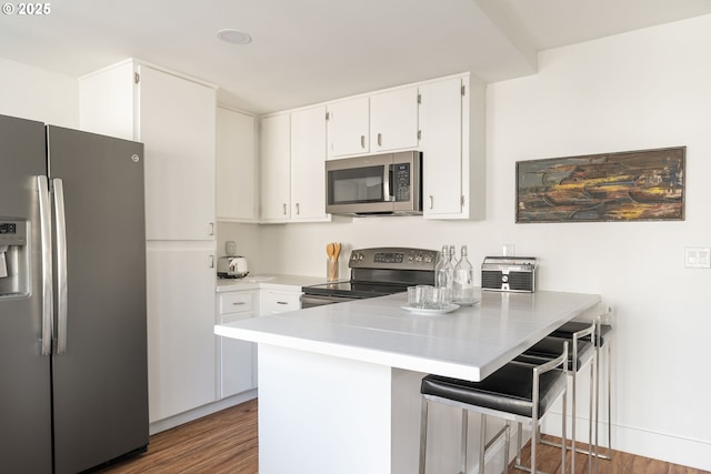 1368 Boca Ratan Dr, Lake Oswego, OR 97034 - kitchen featuring appliances with stainless steel finishes, a peninsula, wood finished floors, and white cabinets