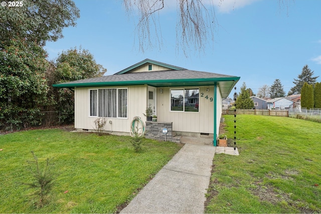 bungalow-style home featuring crawl space, roof with shingles, a front lawn, and fence