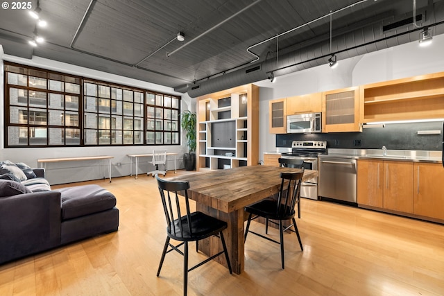 dining area featuring track lighting, sink, and light wood-type flooring