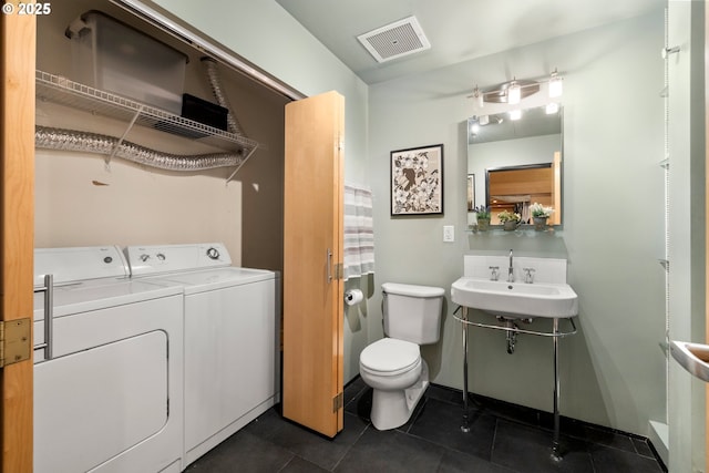 bathroom with tile patterned flooring, sink, washer and dryer, and toilet