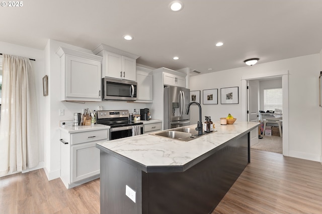 1410 NW Keasey St, Roseburg, OR 97471 - kitchen with appliances with stainless steel finishes, a sink, a center island with sink, light wood-style floors, and white cabinets