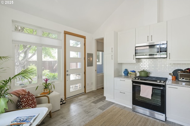 7228 N Villard Ave, Portland, OR 97217 - kitchen featuring range with gas cooktop, stainless steel microwave, light wood-type flooring, backsplash, and white cabinetry