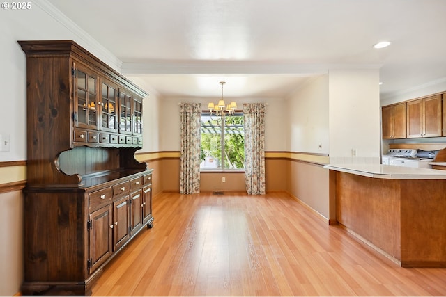 kitchen with independent washer and dryer, pendant lighting, light wood finished floors, a chandelier, and glass insert cabinets