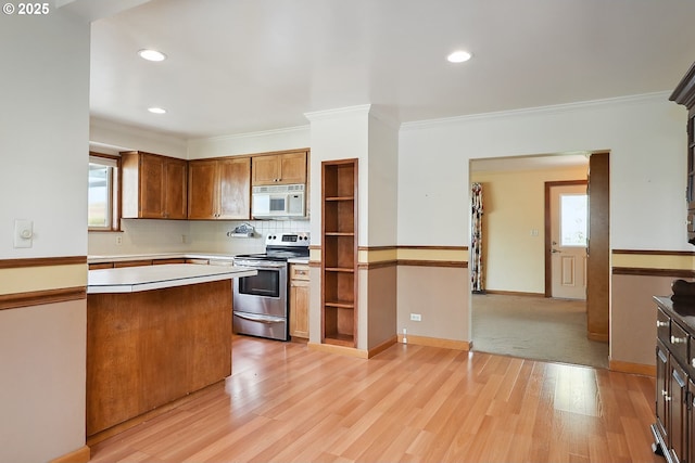 kitchen with crown molding, white microwave, light wood finished floors, tasteful backsplash, and stainless steel electric stove