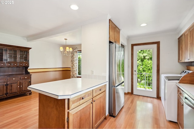 kitchen featuring washing machine and dryer, light wood-style floors, a chandelier, appliances with stainless steel finishes, and a wealth of natural light