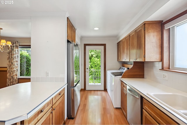 kitchen with light wood-style floors, light countertops, appliances with stainless steel finishes, and washing machine and dryer