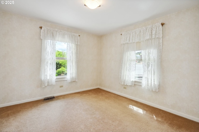 spare room featuring carpet floors, baseboards, and visible vents