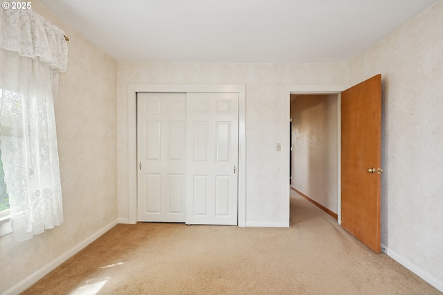 unfurnished bedroom with baseboards, carpet flooring, and a closet