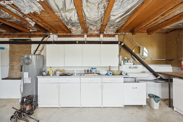 kitchen featuring unfinished concrete floors, white cabinetry, water heater, and light countertops
