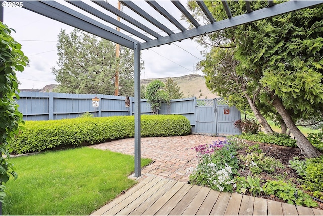 wooden terrace featuring fence, a gate, a pergola, and a lawn