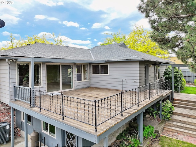 rear view of property featuring a shingled roof, central AC, and a deck
