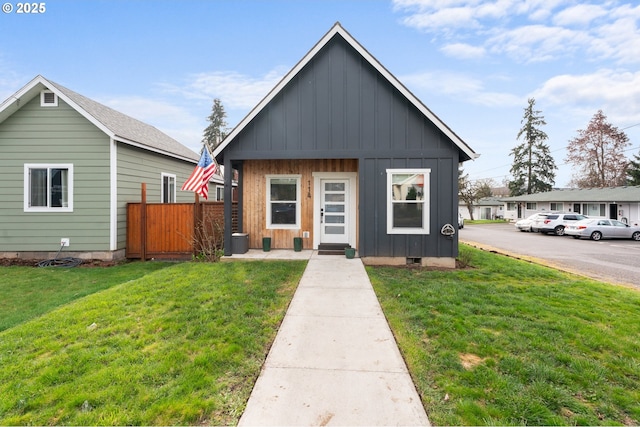 view of front of home with crawl space, board and batten siding, a front yard, and fence