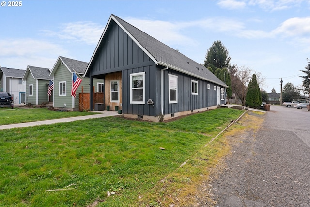 view of front of home with a front yard, board and batten siding, roof with shingles, and crawl space