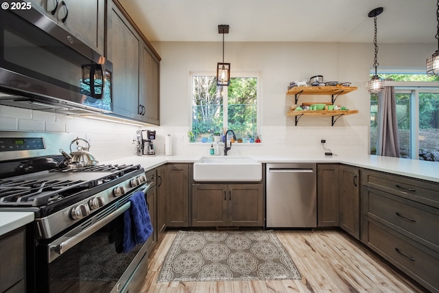 kitchen with stainless steel appliances, decorative light fixtures, sink, and a wealth of natural light