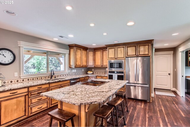10588 Crosby Rd NE, Woodburn, OR 97071 - kitchen featuring appliances with stainless steel finishes, a sink, a kitchen breakfast bar, light stone countertops, and recessed lighting