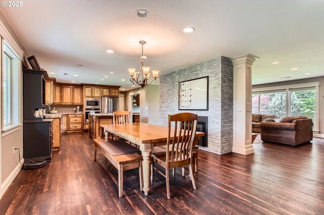 10588 Crosby Rd NE, Woodburn, OR 97071 - dining area with dark wood-style flooring, a chandelier, a fireplace, recessed lighting, and baseboards