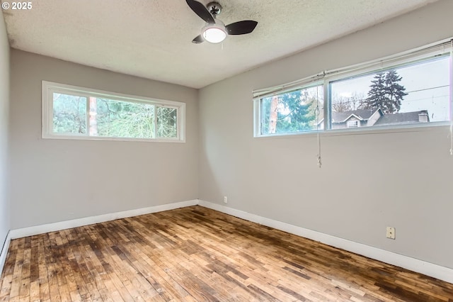 spare room with a textured ceiling, a ceiling fan, baseboards, and wood-type flooring