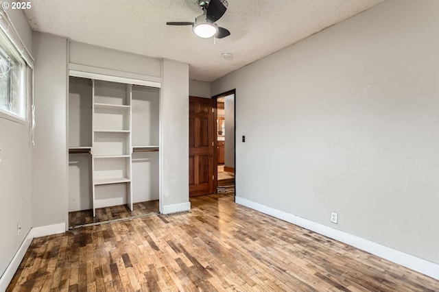 unfurnished bedroom with a textured ceiling, wood finished floors, a closet, baseboards, and ceiling fan