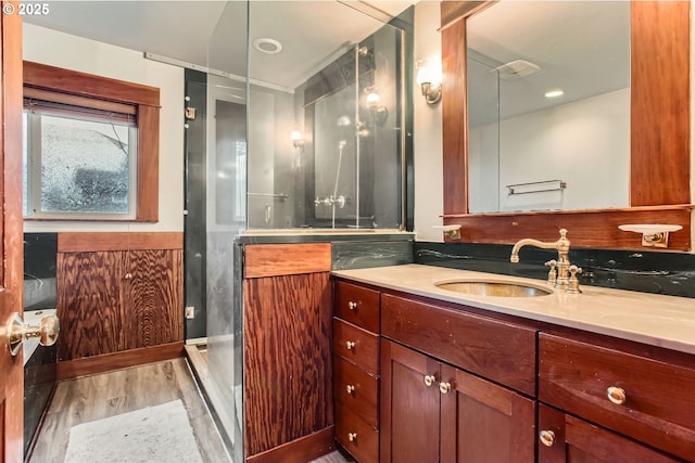 full bathroom featuring a wainscoted wall, a stall shower, vanity, and wood finished floors