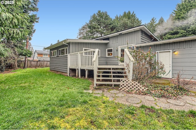 back of property featuring board and batten siding, fence, stairs, a lawn, and a deck