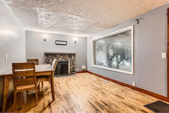 dining space featuring hardwood / wood-style flooring, a fireplace, visible vents, and baseboards