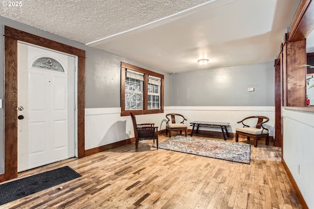 entryway with a textured ceiling, wainscoting, and hardwood / wood-style flooring