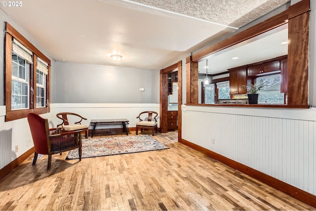 sitting room featuring a wainscoted wall, baseboards, and light wood-type flooring