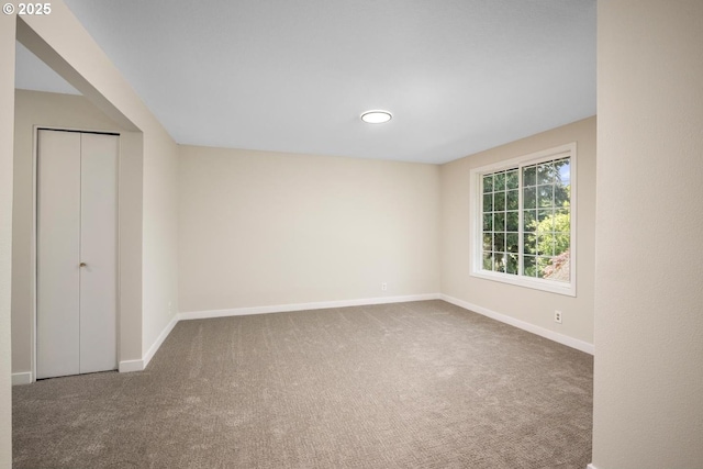 carpeted spare room featuring baseboards