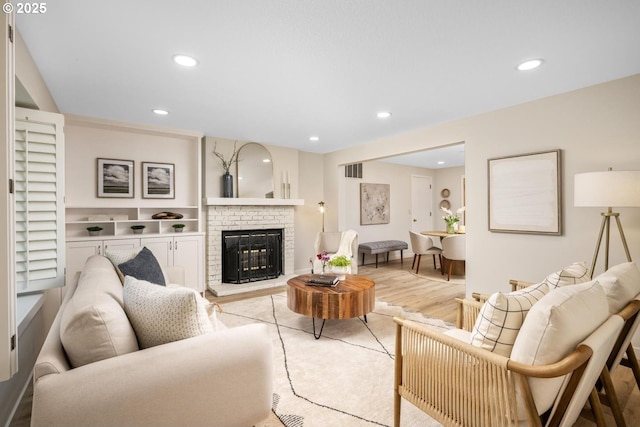 living area with recessed lighting, light wood finished floors, and a brick fireplace