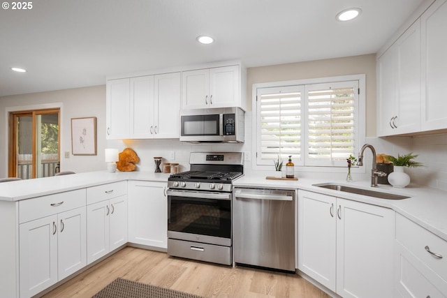 kitchen featuring stainless steel appliances, a sink, healthy amount of natural light, a peninsula, and recessed lighting