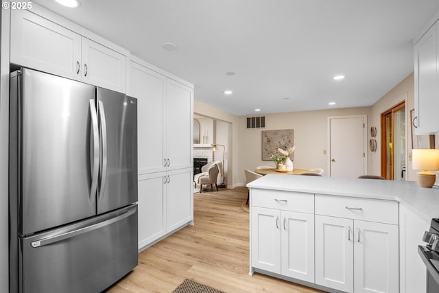 kitchen with freestanding refrigerator, a peninsula, white cabinetry, and recessed lighting