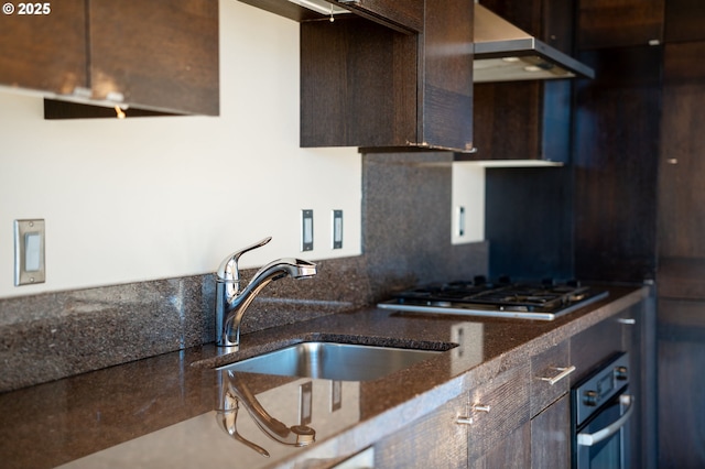 kitchen with appliances with stainless steel finishes, sink, dark brown cabinets, and dark stone counters