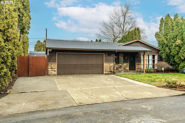 view of front of house with roof with shingles, concrete driveway, an attached garage, a front yard, and stone siding