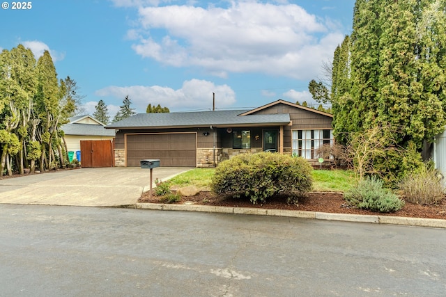 view of front of home with a garage, stone siding, and driveway