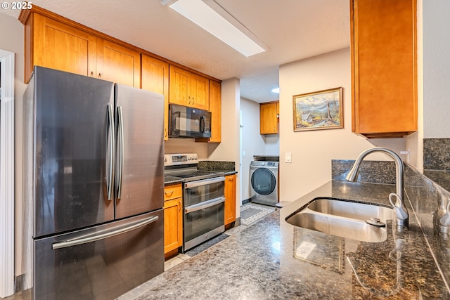 kitchen featuring stainless steel appliances, brown cabinetry, a sink, and washer / dryer