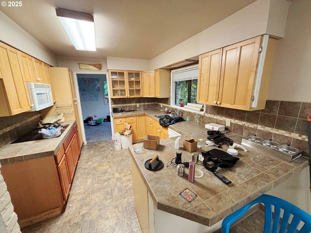 17373 SE Forest Hill Dr, Damascus, OR 97089 - kitchen featuring white microwave, light brown cabinetry, tasteful backsplash, a sink, and glass insert cabinets