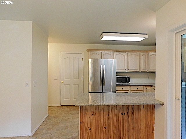 kitchen with light stone countertops, kitchen peninsula, and appliances with stainless steel finishes