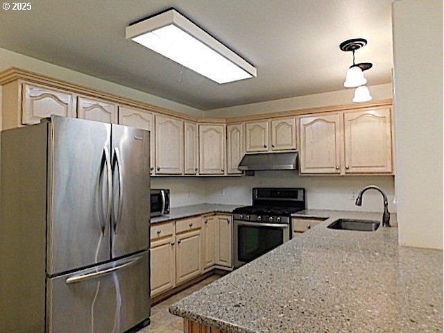 kitchen with light stone countertops, appliances with stainless steel finishes, kitchen peninsula, sink, and pendant lighting