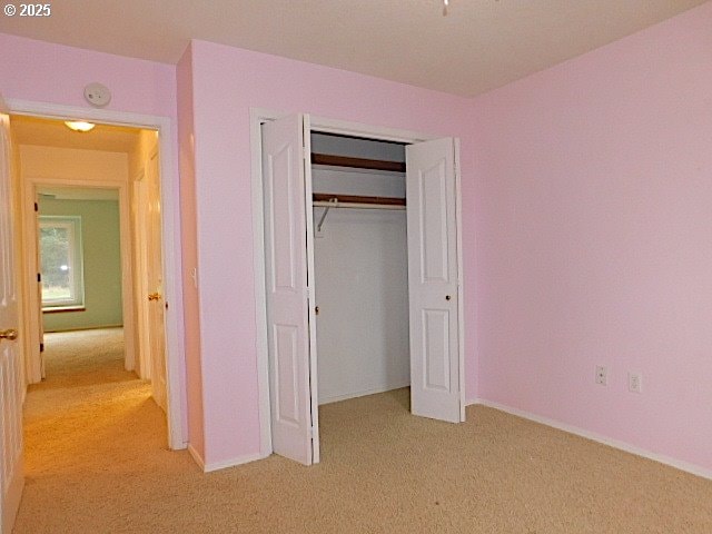 unfurnished bedroom with light carpet and a closet