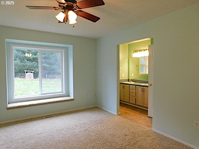 carpeted spare room with ceiling fan and sink