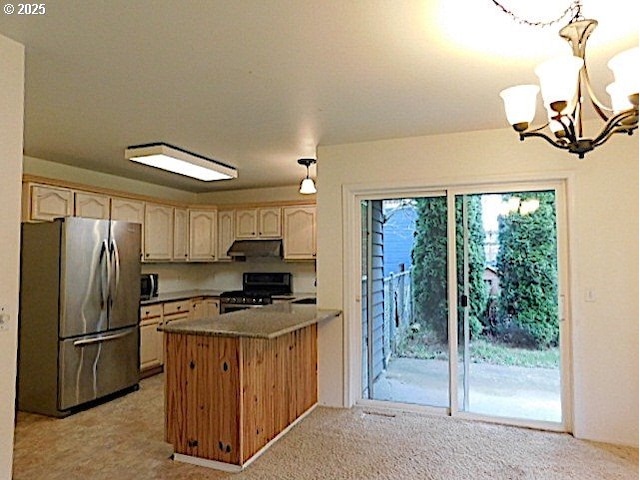 kitchen with a notable chandelier, kitchen peninsula, stainless steel fridge, decorative light fixtures, and black range