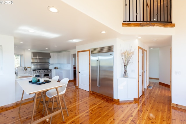 kitchen with high quality appliances, light wood-type flooring, baseboards, light countertops, and recessed lighting