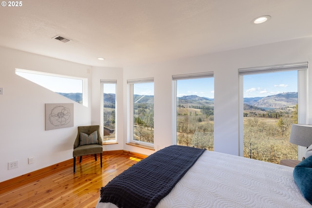 bedroom with recessed lighting, a mountain view, baseboards, light wood finished floors, and visible vents