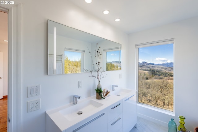 bathroom with a sink, double vanity, and recessed lighting