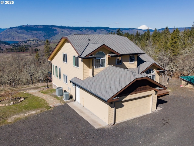 view of front of property with an attached garage, a mountain view, and central AC unit