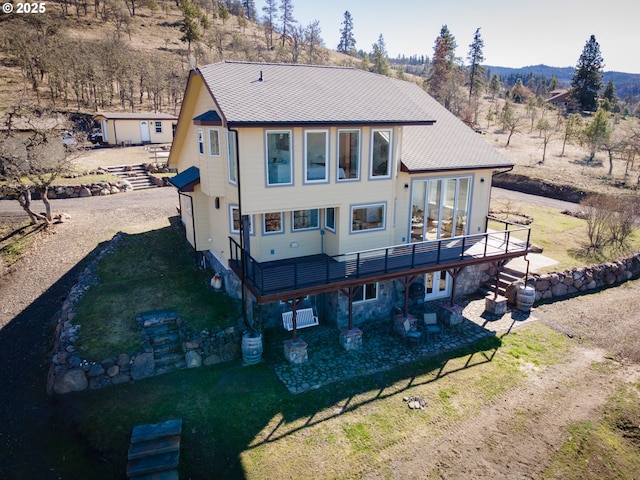 back of property featuring a yard, a deck with mountain view, a patio area, and driveway