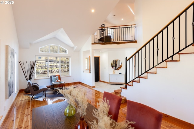 entryway featuring stairway, hardwood / wood-style flooring, baseboards, and high vaulted ceiling
