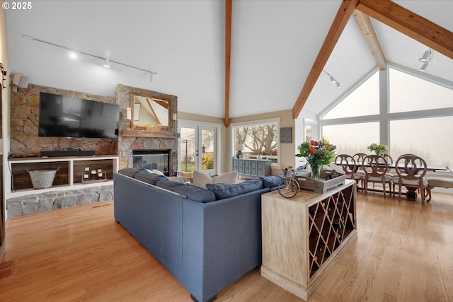 living room featuring lofted ceiling with beams, a stone fireplace, and hardwood / wood-style floors